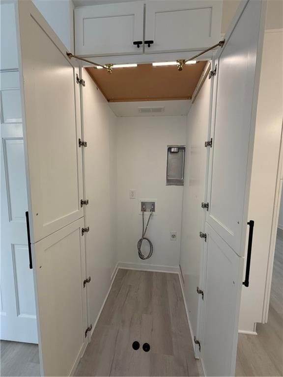 laundry room featuring cabinets, electric dryer hookup, washer hookup, and light hardwood / wood-style flooring