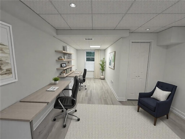 home office featuring a drop ceiling and light wood-type flooring