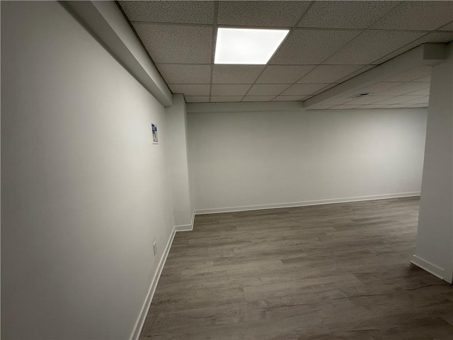 basement with hardwood / wood-style flooring and a paneled ceiling