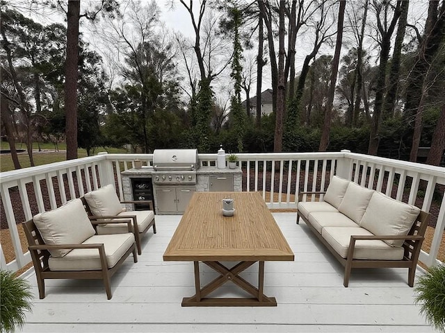 deck with an outdoor kitchen, area for grilling, and an outdoor living space