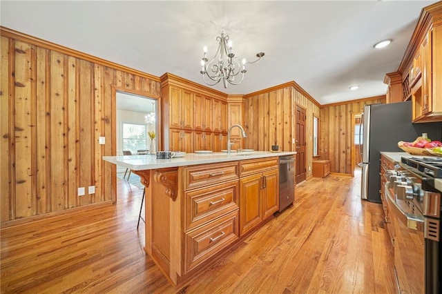 kitchen with a breakfast bar, a kitchen island with sink, hanging light fixtures, stainless steel appliances, and a chandelier