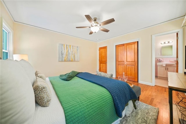 bedroom with light wood-type flooring, ensuite bath, ceiling fan, and sink