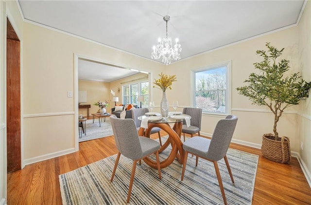 dining area featuring wood-type flooring, a notable chandelier, and ornamental molding