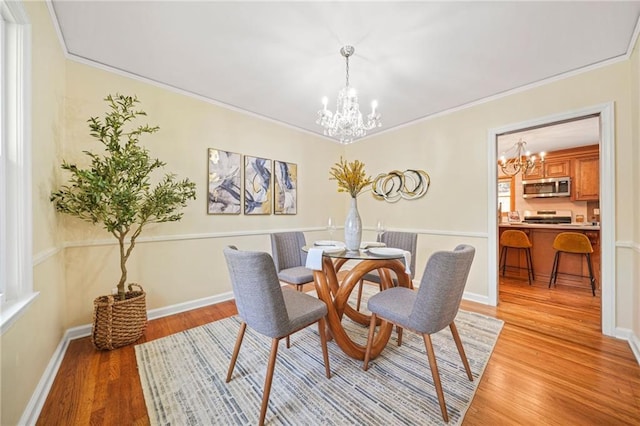 dining area with light hardwood / wood-style floors, an inviting chandelier, and crown molding