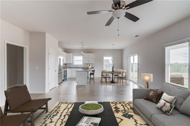 living room featuring ceiling fan, a healthy amount of sunlight, and light hardwood / wood-style flooring