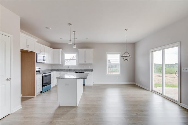 kitchen with a center island, a healthy amount of sunlight, stainless steel appliances, and white cabinetry