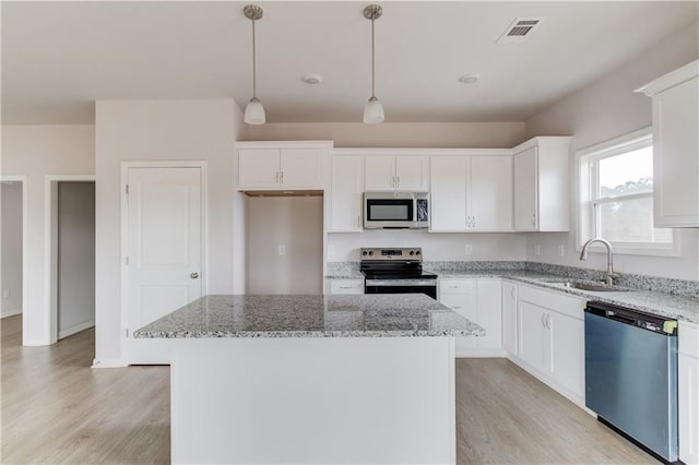 kitchen with stainless steel appliances, pendant lighting, light hardwood / wood-style flooring, white cabinets, and a center island