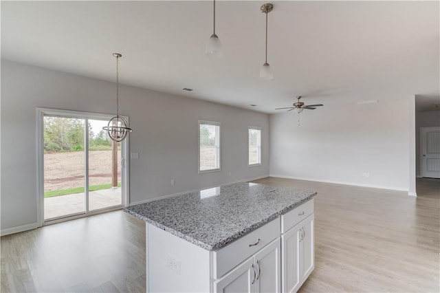 kitchen with white cabinetry, hanging light fixtures, and a wealth of natural light