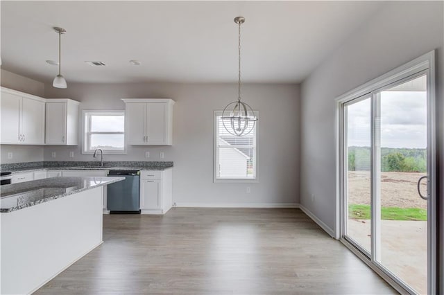 kitchen with pendant lighting, hardwood / wood-style floors, dark stone counters, white cabinets, and stainless steel dishwasher