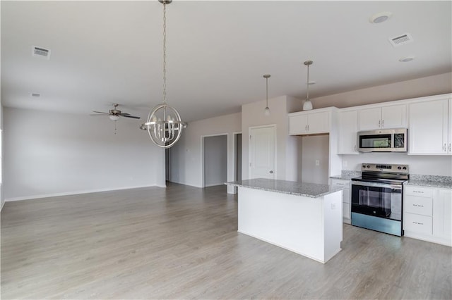 kitchen with appliances with stainless steel finishes, ceiling fan with notable chandelier, white cabinetry, and hanging light fixtures