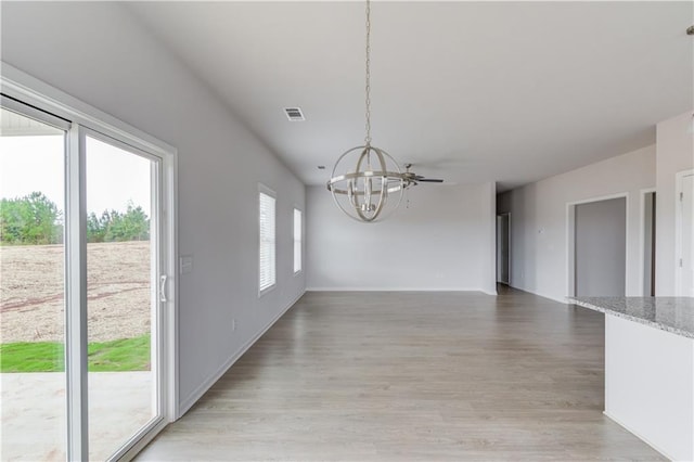 unfurnished dining area with a chandelier, light hardwood / wood-style floors, and plenty of natural light