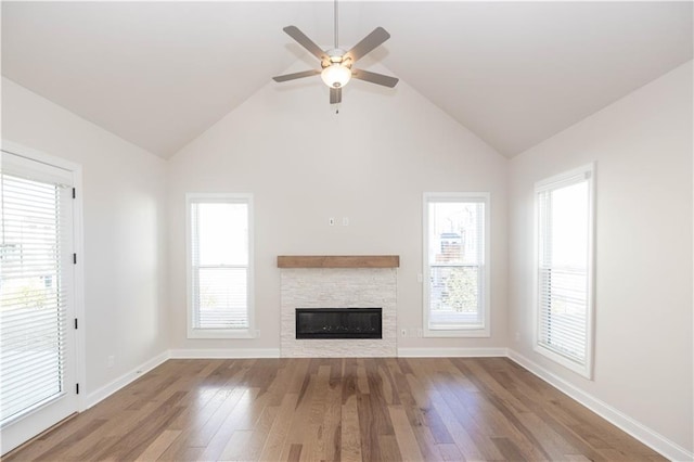 unfurnished living room featuring a fireplace, light hardwood / wood-style flooring, high vaulted ceiling, and ceiling fan