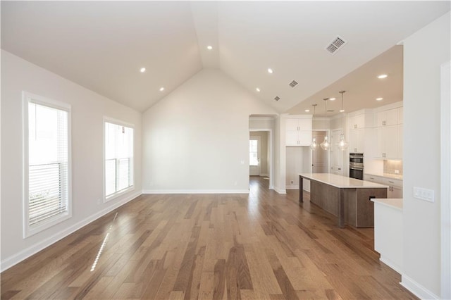 unfurnished living room featuring high vaulted ceiling and light hardwood / wood-style floors