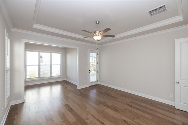 empty room with crown molding, dark wood-type flooring, ceiling fan, and a tray ceiling