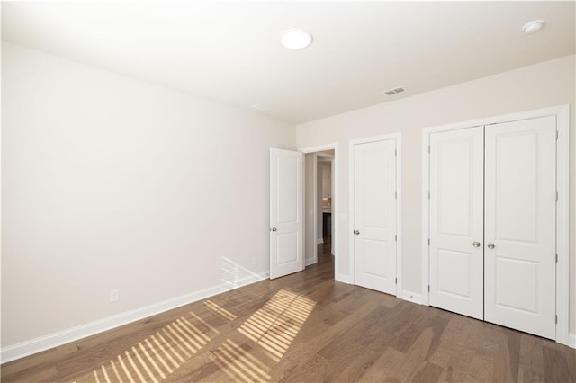 unfurnished bedroom featuring dark hardwood / wood-style flooring and a closet