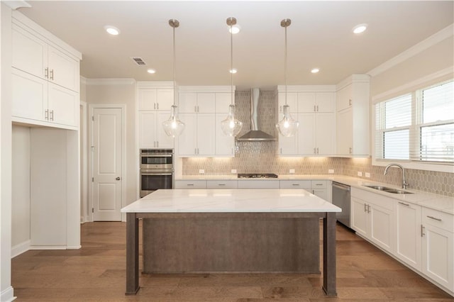 kitchen featuring sink, white cabinetry, stainless steel appliances, a kitchen island, and wall chimney exhaust hood