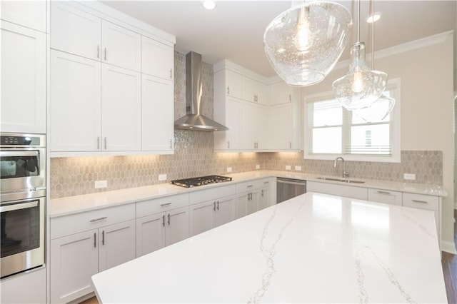 kitchen with white cabinets, decorative light fixtures, sink, and wall chimney range hood