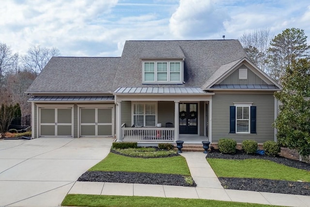 craftsman-style home featuring french doors, covered porch, concrete driveway, an attached garage, and board and batten siding