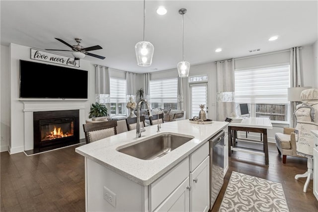 kitchen with hanging light fixtures, a center island with sink, open floor plan, and a sink