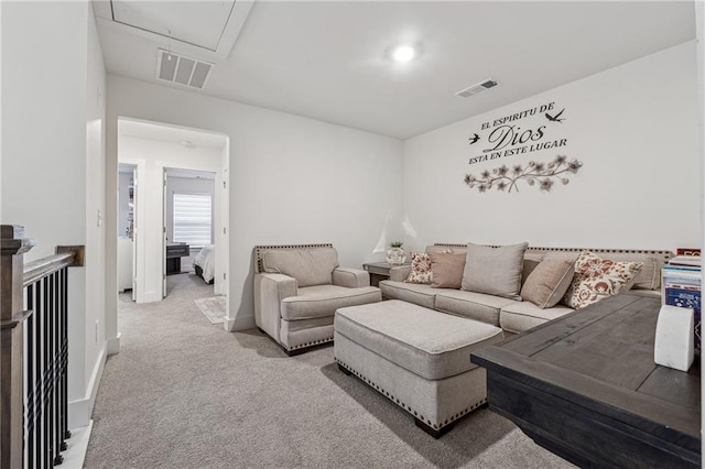 living area with attic access, light colored carpet, visible vents, and baseboards