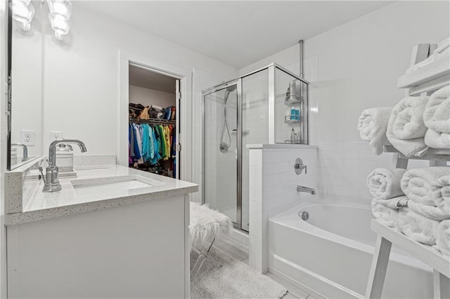 bathroom featuring double vanity, a garden tub, a spacious closet, a shower stall, and a sink