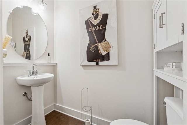 half bath featuring baseboards, toilet, and wood finished floors
