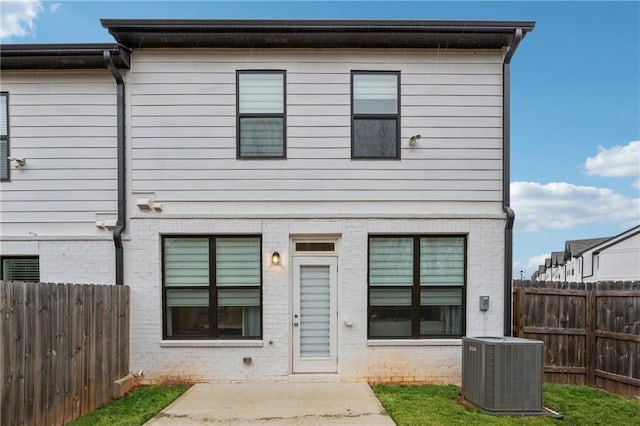 rear view of property with central air condition unit, brick siding, fence, and a patio