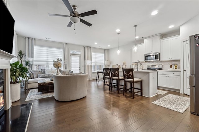 living area featuring a ceiling fan, recessed lighting, and dark wood finished floors