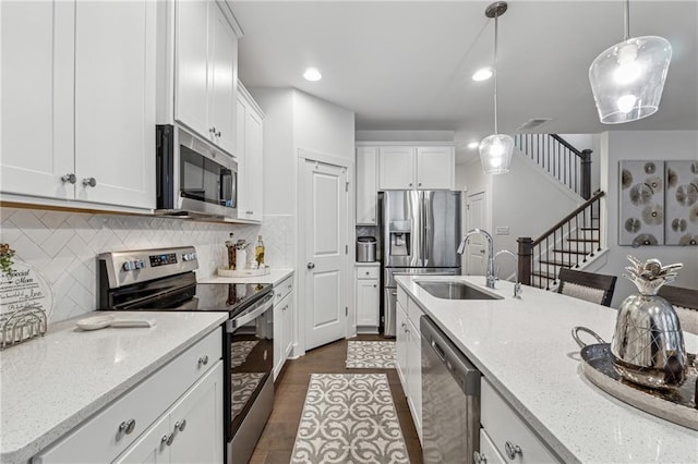 kitchen with stainless steel appliances, light stone counters, white cabinets, and pendant lighting