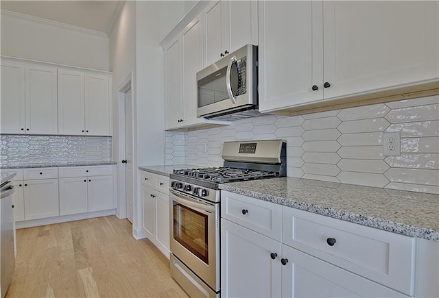 kitchen with white cabinets, light stone counters, stainless steel appliances, and tasteful backsplash