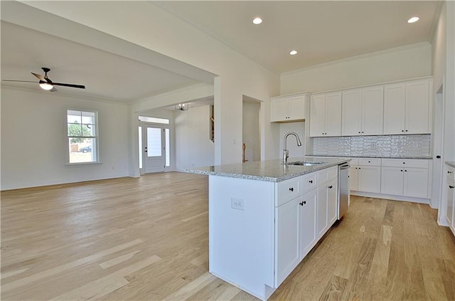 kitchen with white cabinetry, sink, and an island with sink