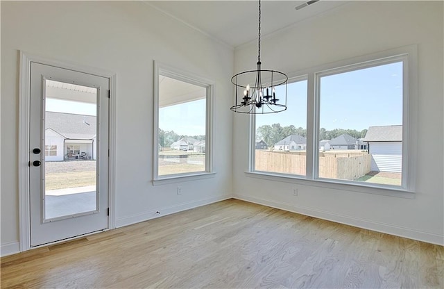 unfurnished dining area featuring a notable chandelier and light wood-type flooring