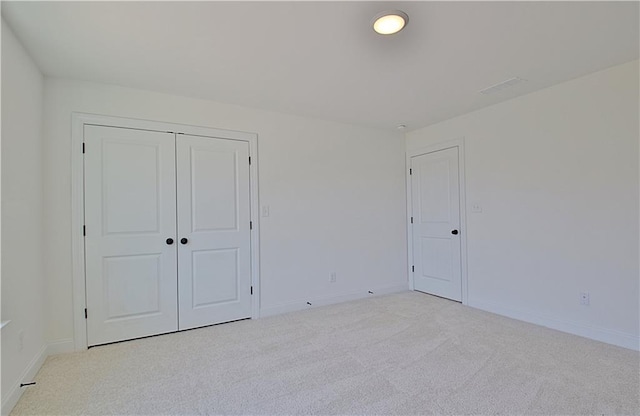 unfurnished bedroom with light carpet and a closet