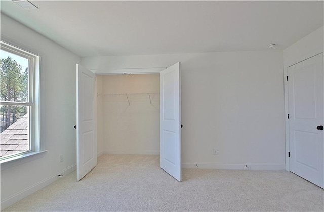 unfurnished bedroom with a closet, light colored carpet, and multiple windows