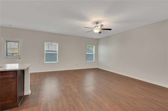 10814 Wheeler Trce, Hampton, GA 30228 - unfurnished living room featuring a ceiling fan, dark wood-type flooring, and baseboards