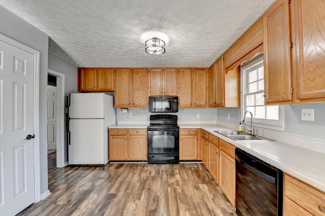 kitchen featuring a textured ceiling, sink, light hardwood / wood-style floors, and black appliances