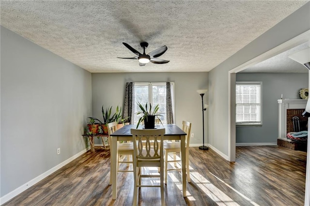 dining room with a fireplace, a textured ceiling, ceiling fan, and dark wood-type flooring