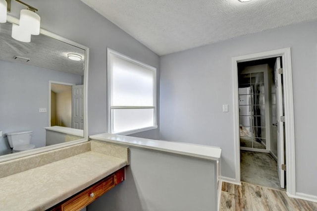 bathroom with a textured ceiling, hardwood / wood-style flooring, and toilet