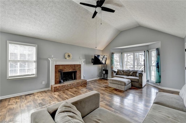 living room with a fireplace, wood-type flooring, vaulted ceiling, and ceiling fan