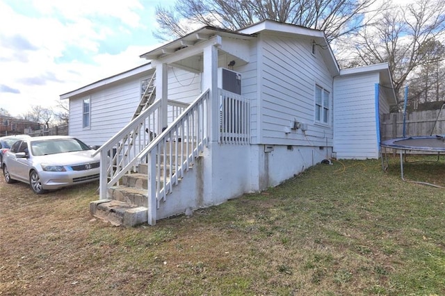 view of side of home featuring a trampoline and a yard