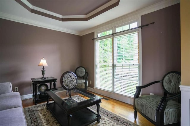 sitting room with a wealth of natural light, ornamental molding, hardwood / wood-style flooring, and a raised ceiling