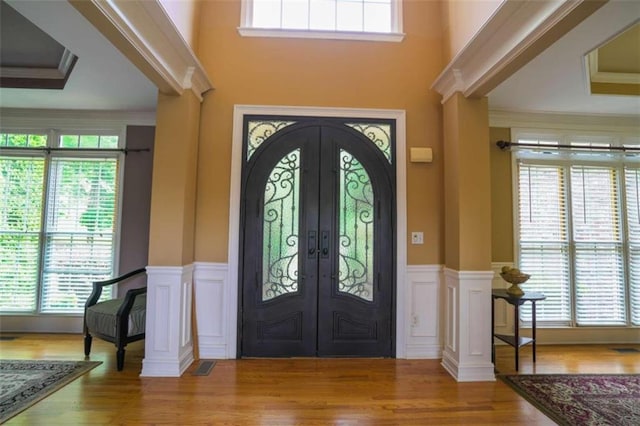 entrance foyer with ornamental molding, french doors, and wood-type flooring