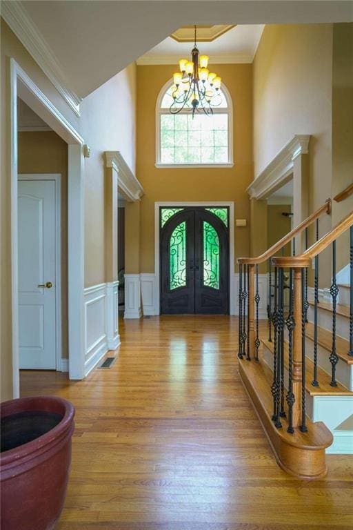 entrance foyer featuring crown molding, a notable chandelier, a high ceiling, and light wood-type flooring