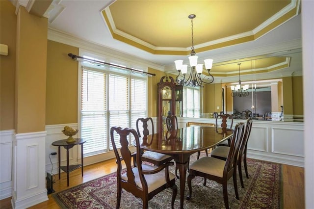 dining area featuring hardwood / wood-style floors, a notable chandelier, crown molding, and a tray ceiling