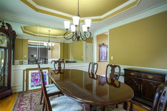 dining room featuring light hardwood / wood-style flooring, crown molding, a chandelier, and a raised ceiling