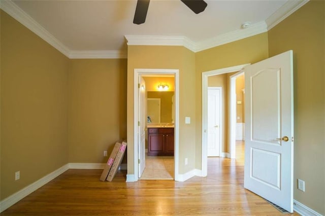 unfurnished bedroom featuring ensuite bath, crown molding, light wood-type flooring, and ceiling fan