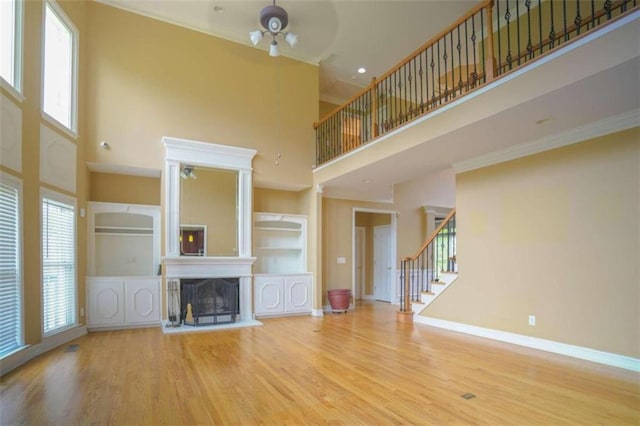 unfurnished living room with a wealth of natural light, hardwood / wood-style flooring, a towering ceiling, and ceiling fan