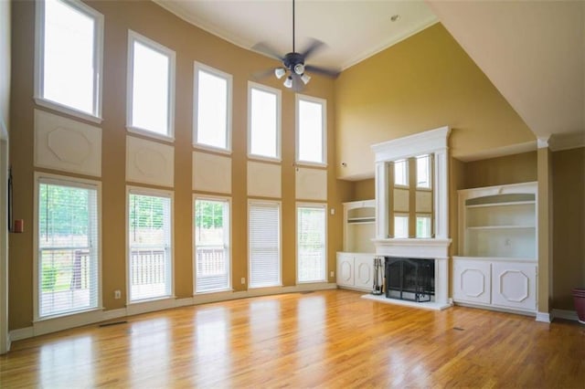 unfurnished living room with a high ceiling, crown molding, light hardwood / wood-style floors, and ceiling fan