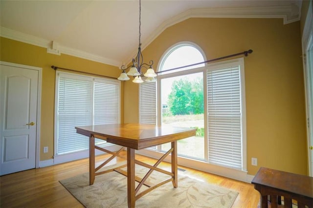 dining room featuring light hardwood / wood-style floors, crown molding, an inviting chandelier, and vaulted ceiling