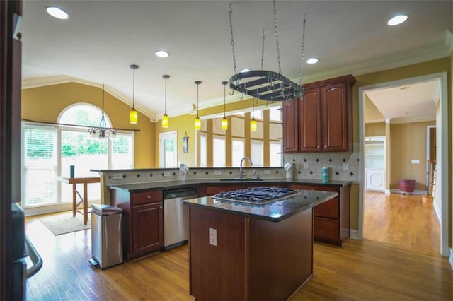 kitchen with kitchen peninsula, light hardwood / wood-style flooring, stainless steel appliances, pendant lighting, and a center island